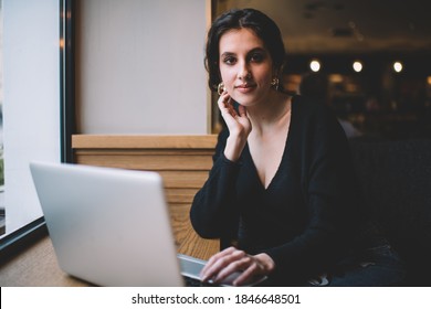 Charming female with gold earrings lean on hand using light gray netbook while working and sitting in cafe in afternoon - Shutterstock ID 1846648501