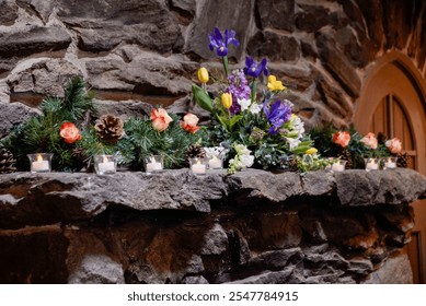 A charming floral arrangement of colorful irises, tulips, and roses, paired with pinecones and candles, set on a rustic stone mantle, creating a cozy and festive atmosphere - Powered by Shutterstock