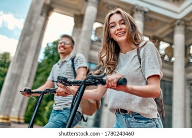 A charming girl and an attractive guy on electric scooters. A couple of students on scooters near the campus. - Powered by Shutterstock