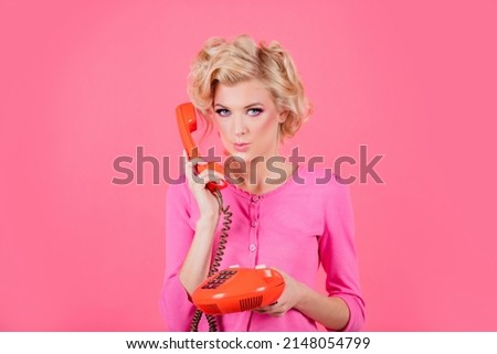 Charming girl holding phone handset, conversation on telephone. Portrait of woman with handset isolated studio background. Fashioned surprised girl talking on the phone.