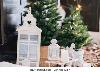 A charming indoor winter decoration features white lanterns, candles, and small Christmas trees with twinkling lights, creating a warm, festive atmosphere for the holiday season. - Powered by Shutterstock