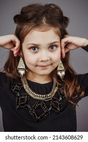 Charming Kid Girl Shows Earrings And Beauty On Background