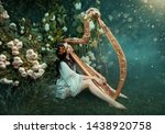 charming lady with dark black hair sits on the frozen grass alone with light white fog, forest nymph with haze plays harp, girl in simple shirt and with bare legs near rose bush, creative photo