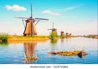 The charming landscape with windmills in Kinderdijk, Netherlands, Europe against a background of cloudy sky reflection in the water.