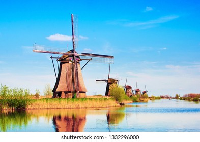 The charming landscape with windmills in Kinderdijk, Netherlands, Europe against a background of cloudy sky reflection in the water.