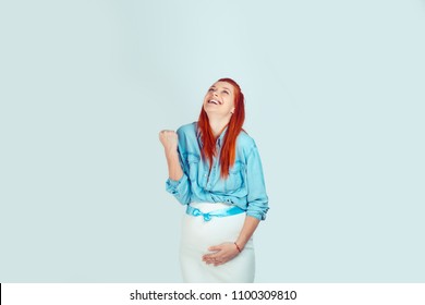 Charming laughing girl touching pregnant belly with blue ribbon having boy and celebrating with fist up on blue background. Yes! I will have a boy concept. Mixed race model, latin hispanic irish woman