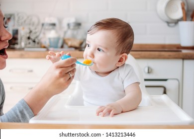 Charming Little Baby Boy 6-8 Months Eating First Food Pumpkin From Spoon With Mom At The Home