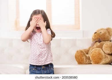 charming little girl covered eyes. nice girl playing hide and seek