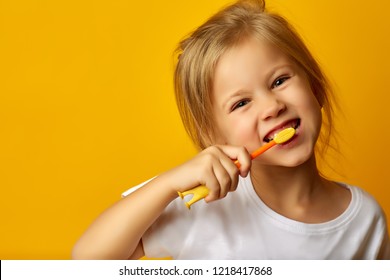 Charming Little Girl In White T-shirt Cleaning Teeth With Colorful Kids Toothbrush Looking At Camera