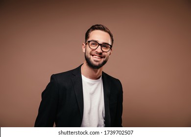 Charming man with glasses smiling on brown background