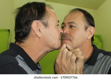 Charming Man In His 50 Years Old Kissing A Mirror, Having His Image Reflected In It, Kissing Himself