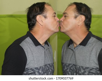 Charming Man In His 50 Years Old Kissing A Mirror, Having His Image Reflected In It, Kissing Himself