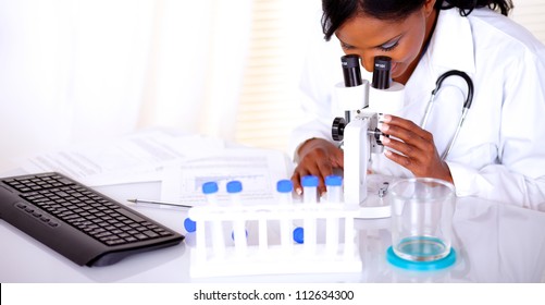 Charming medical doctor woman using a microscope at laboratory - copyspace