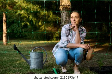 Charming Middle-aged Hispanic Woman, Farmer Amateur, Relaxing During Planting Seedling In The Open Ground Of A Countryside House Backyard. Horticulture, Gardening, Eco Farming Concept, Earth Day