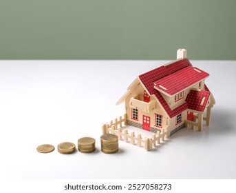 A charming miniature house model sits next to stacked coins, symbolizing finance and investment in real estate. Ideal for economic or budgeting content. - Powered by Shutterstock