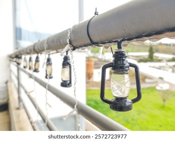 Charming miniature lantern string lights adorn a balcony railing on a rainy day.  Perfect for blogs, websites, or adding a touch of cozy ambiance to your designs.  Ideal for autumn or winter themes.