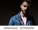 Charming model looking forward while wearing jeans jacket standing on wallpaper studio background