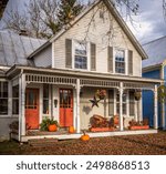 Charming old house during autumn with orange doors, decorated with pumpkins for fall season and Halloween. Photo taken in Montgomery Center, Vermont, New England, United States in October 2023.