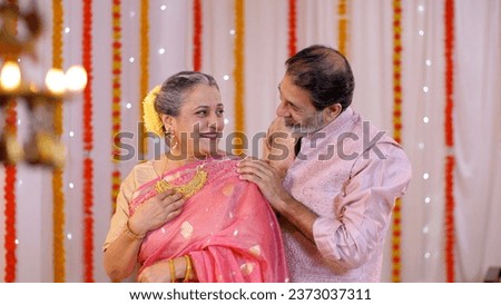 A charming old man giving a Diwali gift to his beautiful wife - putting necklace, old age love, celebrating golden jubilee, happy anniversary, gold necklace. Old couple celebrating Diwali festival ...