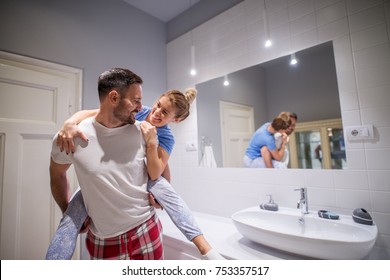 Charming playful love couple in pajamas having a piggyback ride in the bathroom. - Powered by Shutterstock