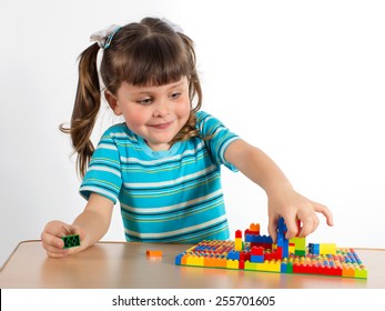 Charming preschooler playing with small constructor. Little girl playing with connecting toy cubes