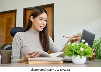 Charming and pretty young Asian female college student doing her project assignment at home, using laptop to search the online information. - Shutterstock ID 2196072981