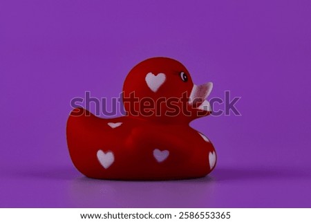 Charming Red Rubber Duck with Heart Patterns Captivatingly Posed Against a Bright Purple Background for a Playful and Whimsical Touch Perfect for Kids and Adults Alike