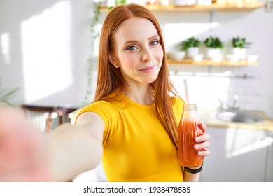 charming redhead food blogger woman drinking juice detox handmade smoothie in kitchen at home - Powered by Shutterstock