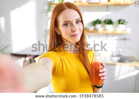 charming redhead food blogger woman drinking juice detox handmade smoothie in kitchen at home