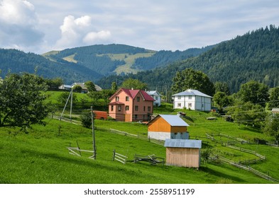 Charming rural village scene featuring quaint houses nestled amidst lush green fields, with scenic mountain views in the background. Carpathian Mountains, Ukraine - Powered by Shutterstock