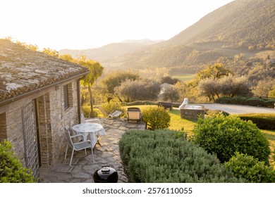 charming rustic house surrounded by lush greenery, overlooking the serene Tuscan countryside. Bathed in soft sunlight, it embodies rural tranquility and natural beauty