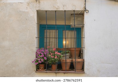 A charming and rustic window set into an old stucco wall, featuring a vibrant turquoise blue wooden frame and protective black iron bars - Powered by Shutterstock - Get 15% off with code: PIKWIZARD15