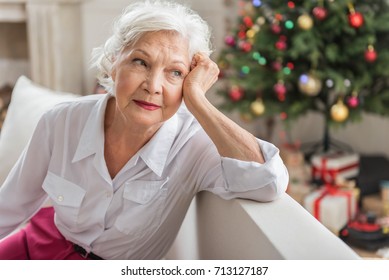 Charming Sad Old Woman Is Sitting On Sofa