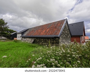 Charming Scandinavian Style Buildings and Architecture  in Tórshavn, the capital city of the Faroe Islands. Grassy field in the foreground of view.  Cloudy blue sky in background of view.   - Powered by Shutterstock