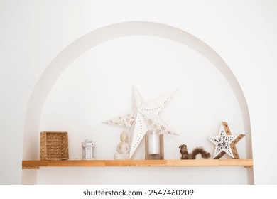 A charming shelf displays various decorative items, including star-shaped ornaments and a small sculpture, set against a light-colored wall to create a cozy atmosphere. - Powered by Shutterstock