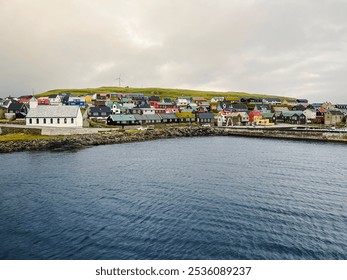 Charming small Nordic island of Nólsoy as Viewed from the North Atlantic Ocean. Colorful Scandinavian style architecture and church line the coast. Located within the archipelago of the Faroe Islands. - Powered by Shutterstock