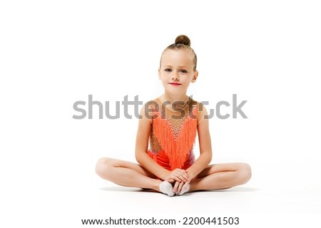 Charming sportive girl sit in studio isolated background in lotus yoga pose, wearing makeup and bright leotard, little gymnastics and acrobatics child