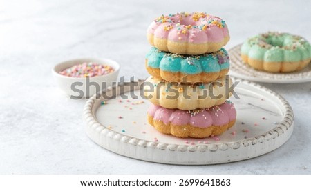 charming stack of uniquely shaped donuts, frosted in pastel hues and decorated with sprinkles, presented on a rustic plate alongside a small bowl of extra toppings.