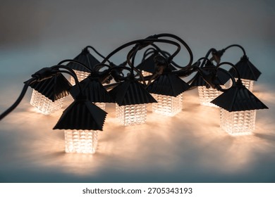 Charming string lights featuring small house-shaped lanterns glowing softly.
