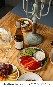 A charming table scene features an array of fresh vegetables, a bottle of wine, and glasses, creating a warm atmosphere for sharing delicious moments with friends