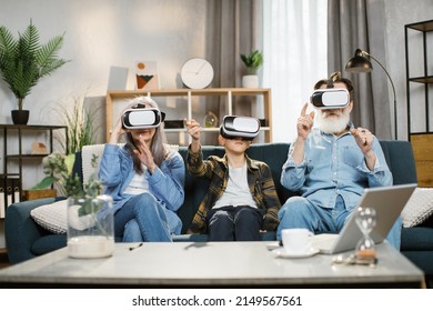 Charming teenage grandson with his grandmother and grandfather watching in modern augmented vr headset reality glasses In the living room at home. - Powered by Shutterstock