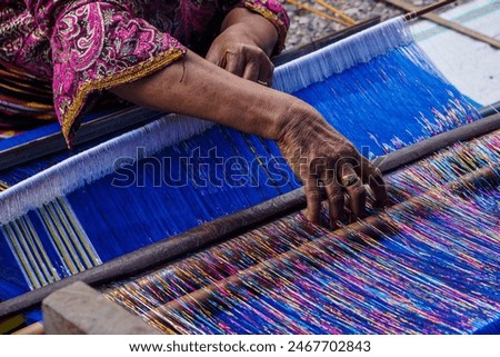 Charming Threads ,Tradition Embracing the timeless art of weaving, this image showcases the grace and skill of a woman as she weaves on a loom. 