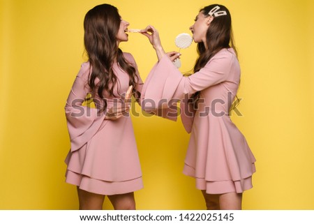 Charming twins eyes with lollipops and posing
