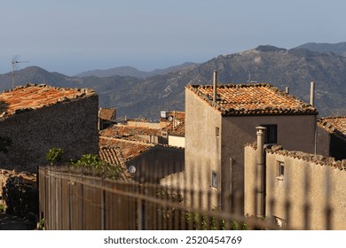 Charming view of terracotta rooftops in a rustic village, set against a backdrop of mountains and distant coastal scenery, capturing warm Mediterranean light and tranquil atmosphere - Powered by Shutterstock