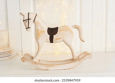 A charming white rocking horse stands on a wooden base, gracefully balanced against a softly lit background, creating a nostalgic and inviting atmosphere in the room. - Powered by Shutterstock