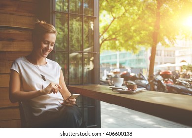 Charming woman with beautiful smile reading good news on mobile phone during rest in coffee shop, happy Caucasian female watching her photos on cell telephone while relaxing in cafe during free time  - Shutterstock ID 406600138