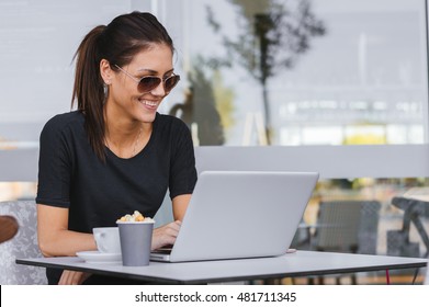 Charming woman with beautiful smile reading good news on laptop during rest in coffee shop, happy Caucasian female working in cafe. Overtime. - Shutterstock ID 481711345