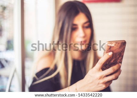 Charming woman with beautiful smile reading good news on mobile phone during rest in coffee shop, happy Caucasian female watching her photos on cell telephone while relaxing at home during free time