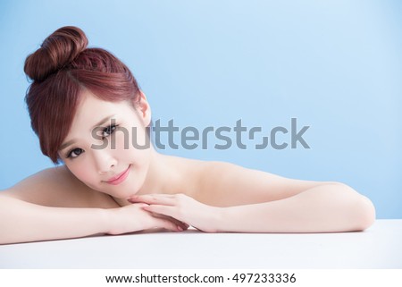 charming woman face smile to you close up while lying isolated on blue background, asian girl