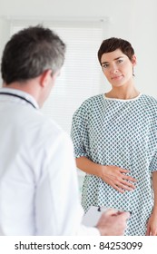 Charming Woman In Hospital Gown Talking To Her Doctor In A Room